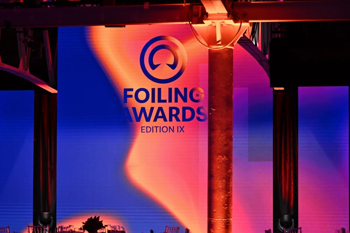 Schermo di scena con logo 'Foiling Awards Edition IX' e colonne, illuminazione colorata sul palco