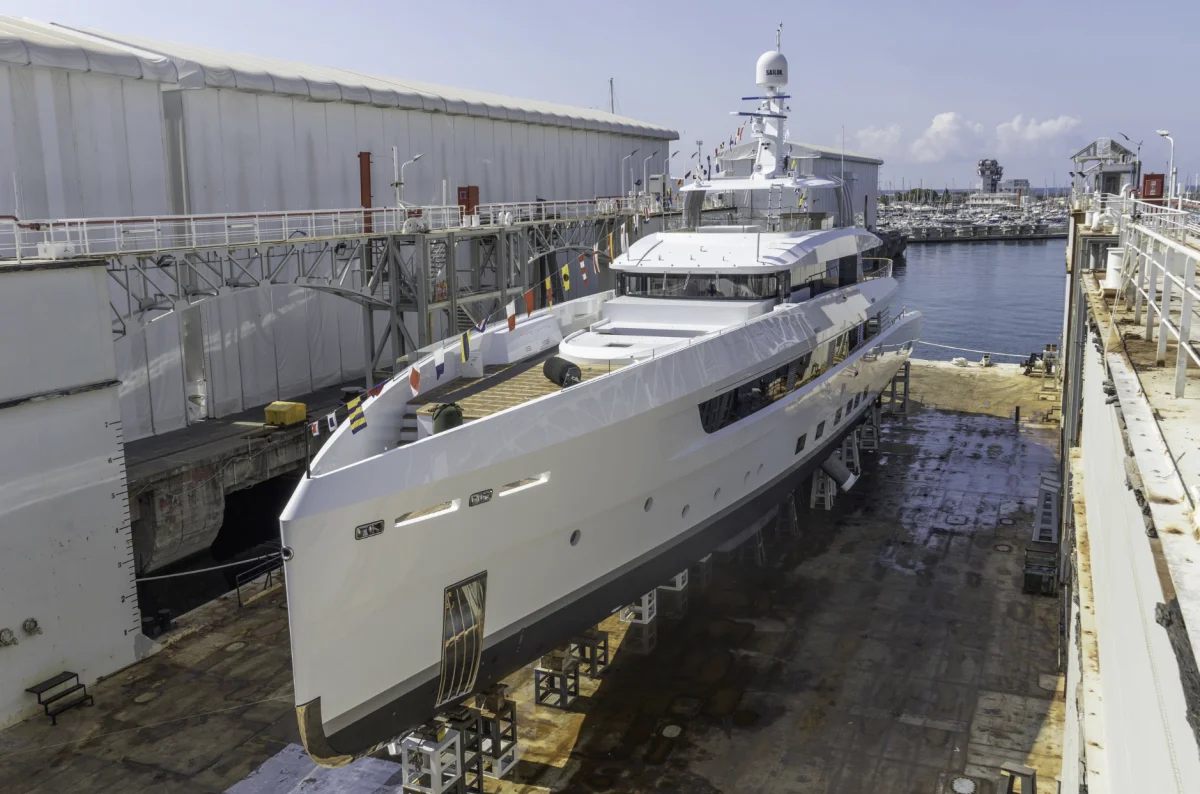 Yacht di lusso in bacino di carenaggio, vista di prua in cantiere navale pronta per lavori o consegna, adatta come immagine principale.