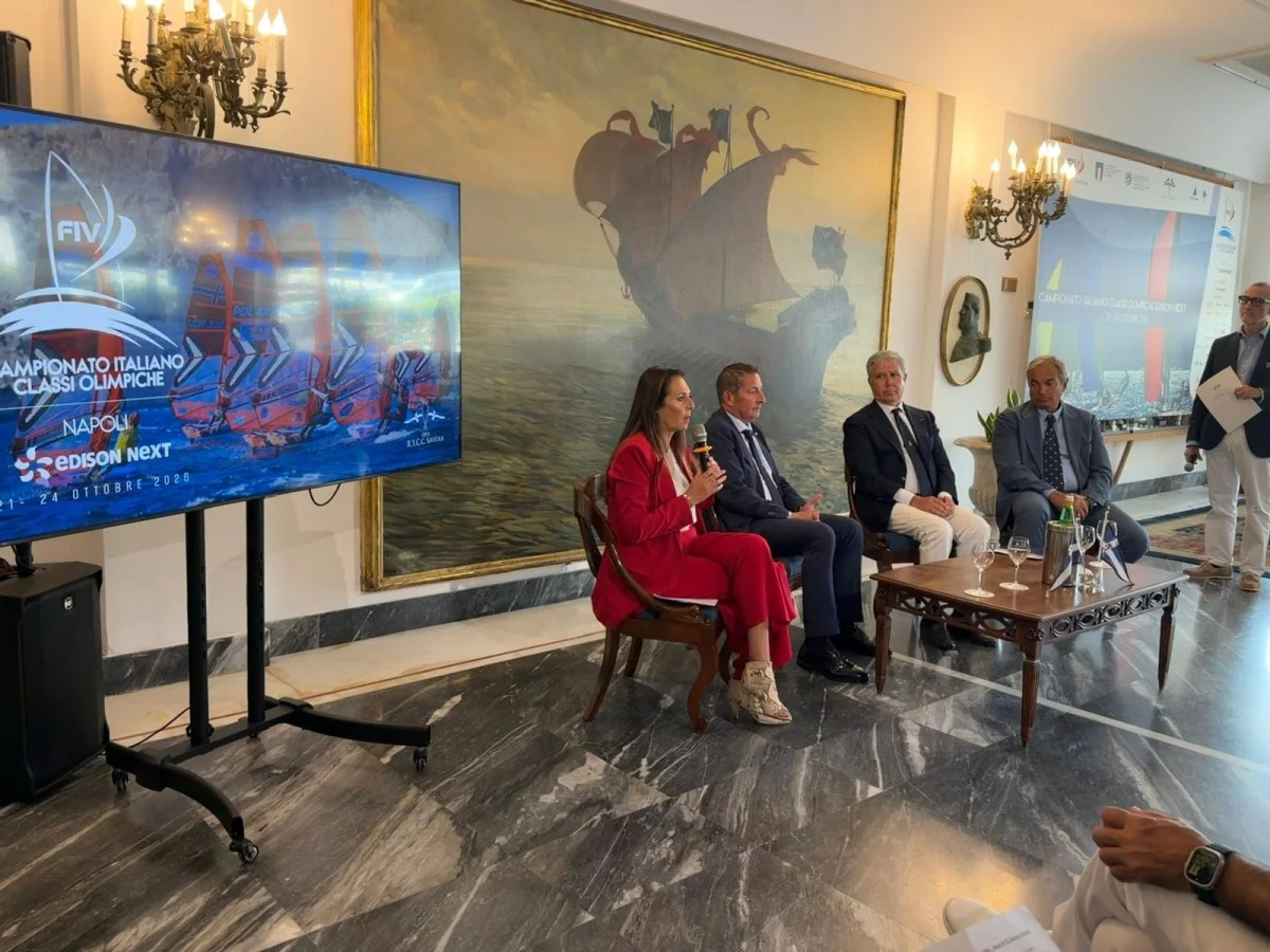 Conferenza stampa di presentazione del Campionato Italiano Classi Olimpiche a Napoli: relatori seduti in una sala, schermo con locandina.