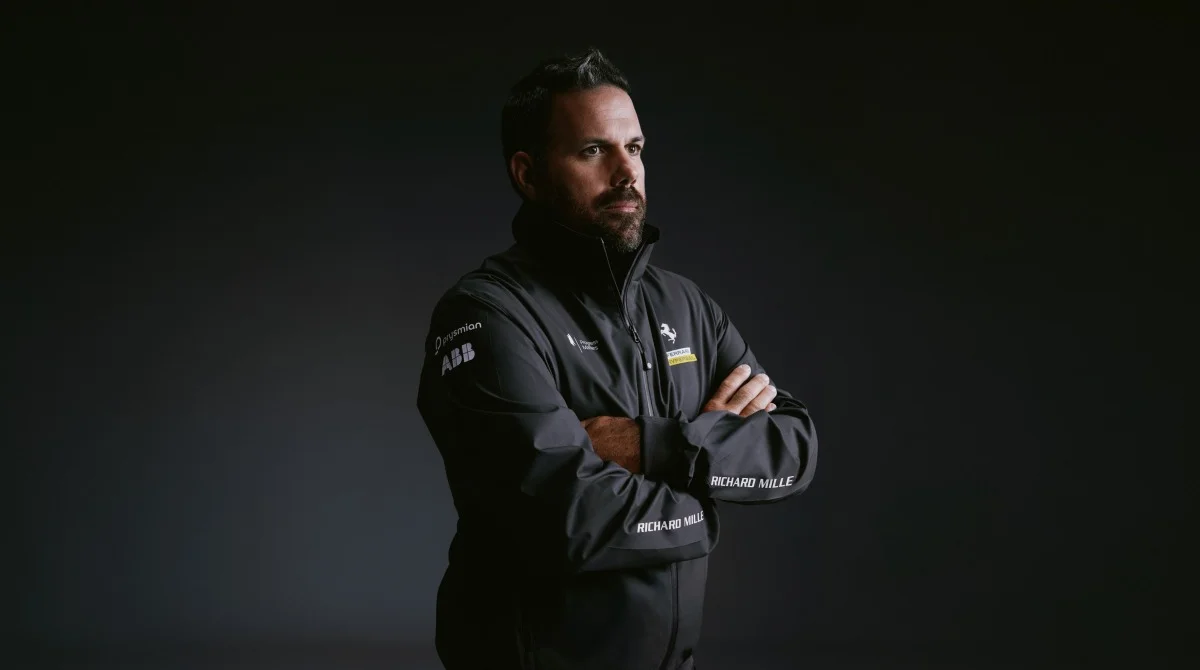 Ritratto a mezzo busto di un uomo con giacca tecnica Ferrari Hypersail, posa laterale su sfondo scuro, utile per focus persone/biografie.
