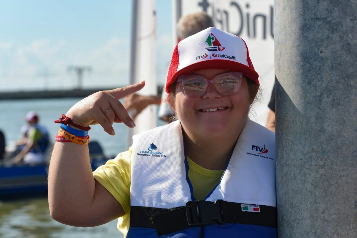 Ritratto ravvicinato di una giovane velista con cappellino FIV/UniCredit e giubbotto di salvataggio, sorridente.