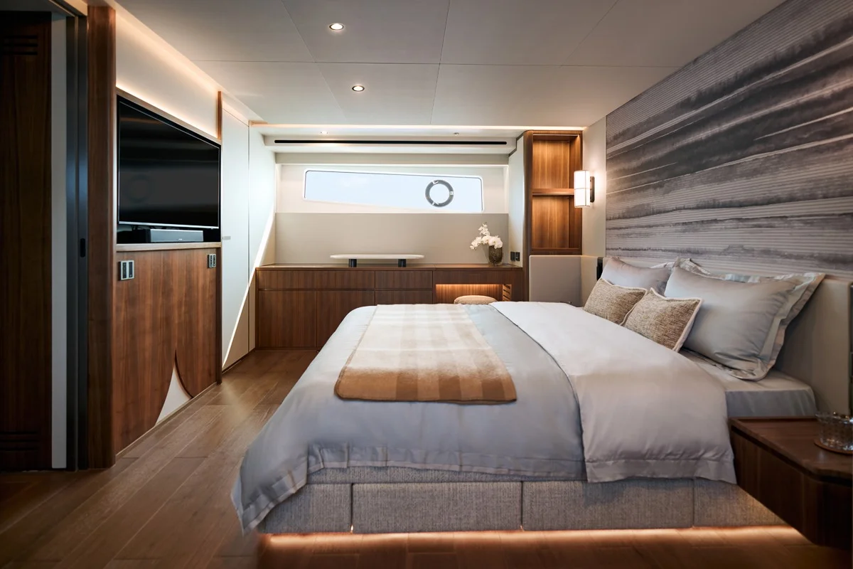 Cabina armatoria con letto matrimoniale, TV, boiserie in legno, pannello decorativo e illuminazione soffusa.