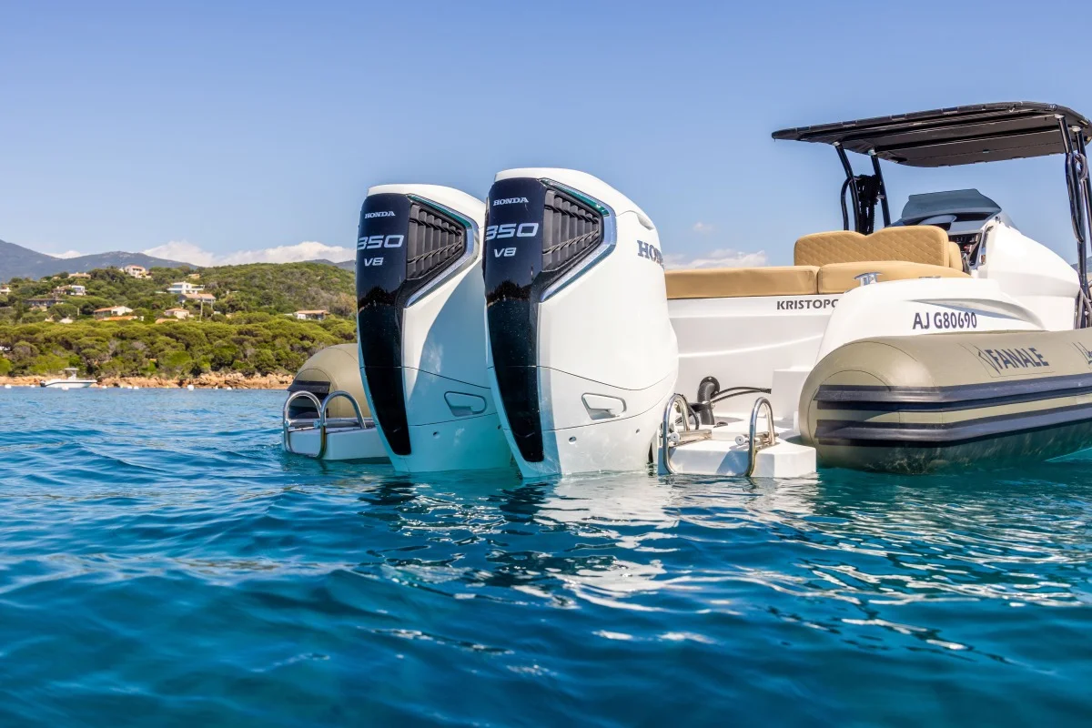 Prua di gommone con doppio fuoribordo Honda 350 V8 in primo piano sull'acqua limpida, dettaglio motori e specchio di poppa.
