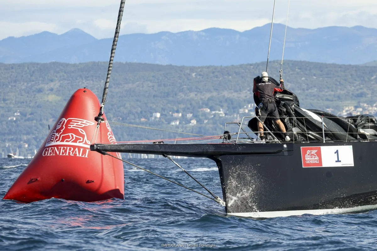 Primo piano poppa e prua di un TP52 vicino boa rossa Generali, dettaglio di manovre e sponsor durante la regata.
