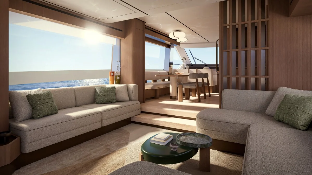 Interno salone elegante e luminoso con divani, tavolo da pranzo e grandi finestrature affacciate sul mare.
