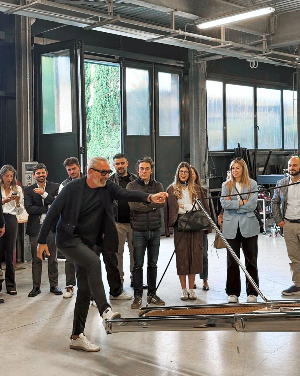 Scena indoor con presentazione dimostrativa davanti a un pubblico, buona per illustrare eventi o visite in azienda.