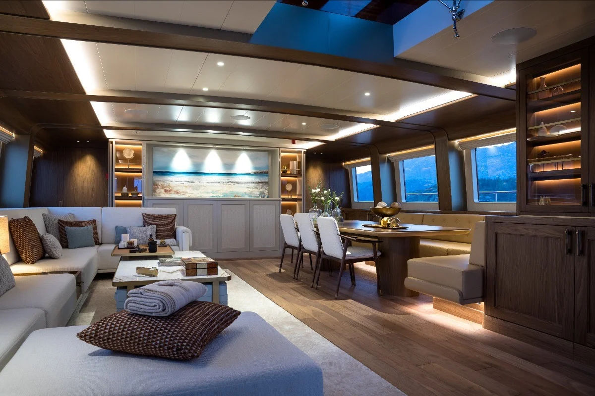 Salone con zona living, divani chiari, tavolino, tavolo da pranzo sullo sfondo e illuminazione calda.