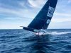 Imbarcazione da regata foiling con vele nere recanti la scritta United By The Ocean sul mare aperto