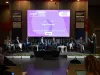 Relatori seduti sul palco davanti a uno schermo con la scritta Blue Finance, mentre una donna parla al microfono; in primo piano il pubblico.