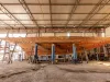 Scafo in legno di uno yacht sostenuto su cavalletti all'interno di un capannone di cantiere