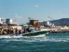 Barca da pesca a motore che naviga vicino al molo con canne da pesca in evidenza