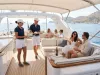 Due membri dell'equipaggio in polo blu e pantaloncini bianchi servono drink e stuzzichini a ospiti rilassati sul ponte di uno yacht