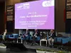 Quattro relatori seduti su poltrone blu sul palco di un convegno, davanti a un grande schermo con il titolo 