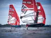 Surf foil in regata con vele rosse, tra cui ITA 155 con il nome L. Tomasini visibile