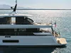 Yacht Azimut bianco in navigazione, vista laterale della poppa con terrazze, flybridge e bandiera italiana, su mare calmo con costa sullo sfondo