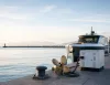 Banchina al tramonto con elica in bronzo, unità di accumulo collegata con cavo, colonnina di ricarica e barca ormeggiata sul mare