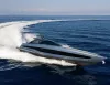 Yacht sportivo dallo scafo grigio metallizzato in alta velocità in mare aperto, con una lunga scia bianca in curva e bandiera italiana a poppa