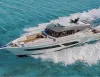 Yacht a motore bianco con hardtop grigio in navigazione su mare turchese, con ampia scia e prendisole a prua visti dall'alto