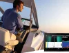 Uomo al timone di un motoscafo con schermi di navigazione e sonar al tramonto.