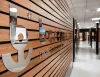 Logo cromato Besenzoni su parete in legno a doghe, con la scritta "Dal 1967" e un corridoio luminoso sullo sfondo