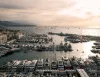 Veduta aerea di un porto affollato di yacht a motore all'ormeggio al tramonto, con costa e mare sullo sfondo