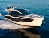 Motor yacht bianco con scafo scuro e ampie vetrate in navigazione veloce sul mare blu, con scia bianca a poppa