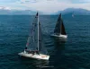 Veduta aerea di due barche a vela con vele scure sul lago, una con scafo bianco e numero 78, con montagne sullo sfondo