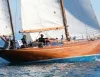 Scafo a vela in legno con equipaggio a bordo che naviga su mare calmo