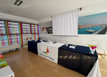 Sala conferenze con tavolo per relatori, schermo e striscioni con il logo Marina Cala de' Medici