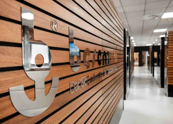 Logo cromato Besenzoni su parete in legno a doghe, con la scritta 