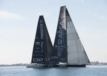 Due maxi yacht con vele nere affiancati in regata sull'acqua calma, con le scritte Prosecco DOC e Arca sulle vele