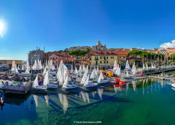 Porto con numerose derive e imbarcazioni allineate sotto il sole, riflessi nell'acqua