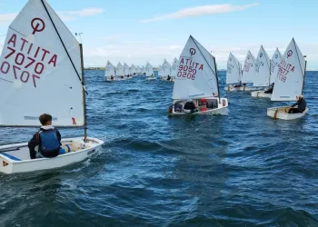 Derive Optimist in regata sullo specchio d'acqua del Lido di Venezia con vele bianche e vento variabile