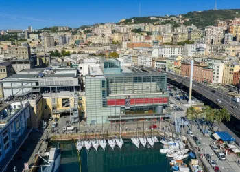Veduta aerea del Galata Museo del Mare e della Darsena con barche a vela ormeggiate, la città di Genova e le colline sullo sfondo