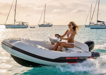 Donna al timone di un tender RIB Novaq in mare con barche a vela sullo sfondo