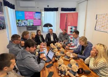 Gruppo di persone attorno a un tavolo con laptop e numerosi peluche a forma di cane