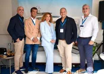 Persone in piedi davanti al render del superyacht Romeo nello stand a Monaco