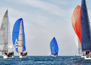 Barche a vela con spinnaker colorati in mare, vele spiegate e scia sull'acqua
