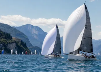 Due Melges 32 con spinnaker bianchi in regata sul Lago di Garda, montagne e altre barche sullo sfondo