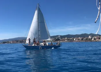 Barca a vela con persone a bordo in mare davanti alla costa
