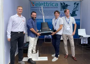 Quattro uomini allo stand Velettrica mostrano il pod ibrido Drive-Pod-16 durante il Salone Nautico di Genova.