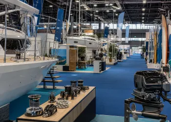 Stand con barche, motori e accessori esposti in un ampio padiglione fieristico con moquette blu