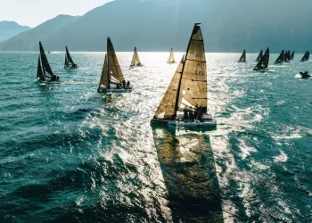 Flotta di imbarcazioni RS21 in regata su acque costiere con montagne sullo sfondo