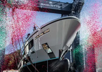 Prua di un superyacht sospeso sotto la gru Baglietto durante il varo, tra coriandoli rossi, verdi e bianchi