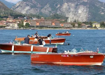Motoscafi d'epoca in legno sul Lago Maggiore con la riva e le montagne sullo sfondo