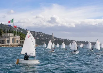 Numerose derive Optimist in regata davanti al lungomare di Barcola con bandiere sullo sfondo