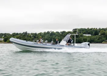 Gommone rigido Titus 10.5 in navigazione con passeggeri lungo una costa alberata