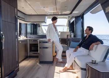 Interno del ponte centrale di uno yacht coupé con cucina, salotto e vista mare