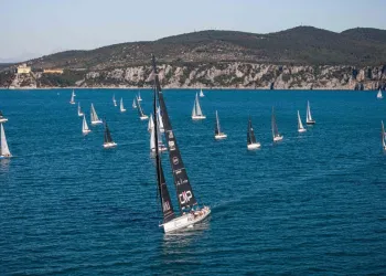 Maxi 90 Prosecco DOC Shockwave³ con vela nera in testa a una flotta durante la regata tra Duino e Miramare