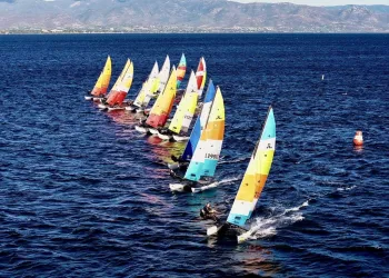 Fila di Hobie Cat 16 con vele colorate in regata sul mare davanti a Cagliari
